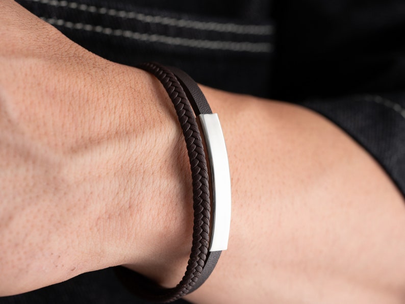 May include: A brown leather bracelet with a silver bar accent.