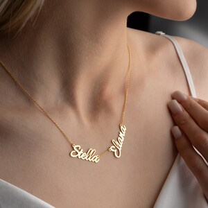 May include: Gold necklace with two names, "Stella" and "Elana", written in a cursive script.