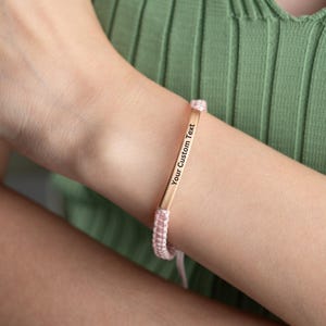 May include: A pink and gold bracelet with a personalized message that reads "Your Custom Text".