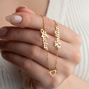May include: Gold necklace with two nameplates, "Lucia" and "Emilia", and a small heart charm.