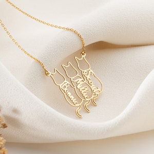 Op de afbeelding: Gouden ketting met drie katten-silhouetten, elk met een gegraveerde naam: Bonnie, Millie en Scout.