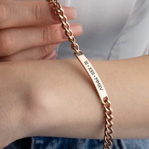 May include: A gold chain bracelet with a rectangular tag engraved with the Roman numerals "III. XXIII. MMXV".