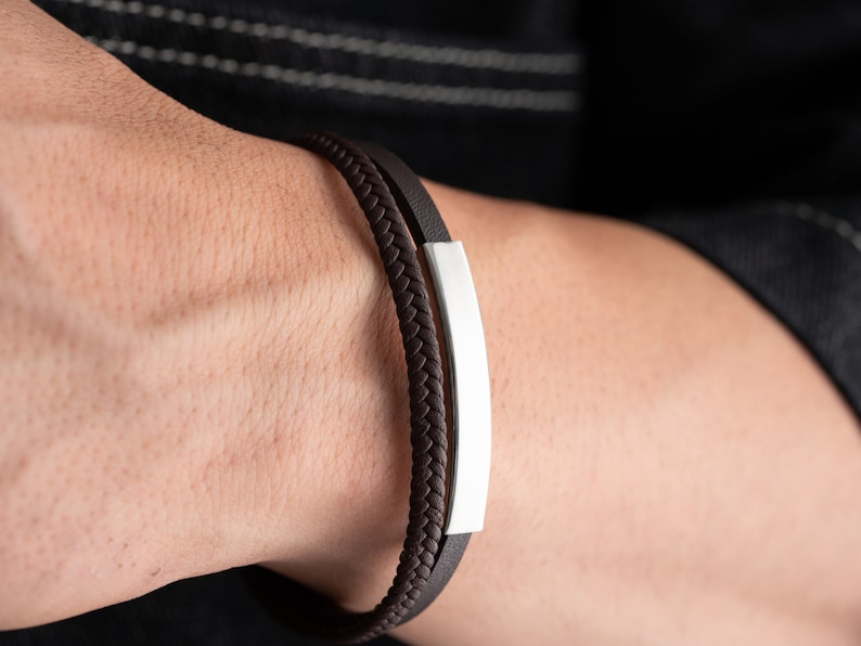 May include: A brown leather bracelet with a silver bar accent.