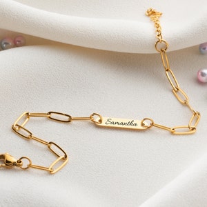 May include: Gold chain bracelet with a personalized nameplate that reads "Samantha".