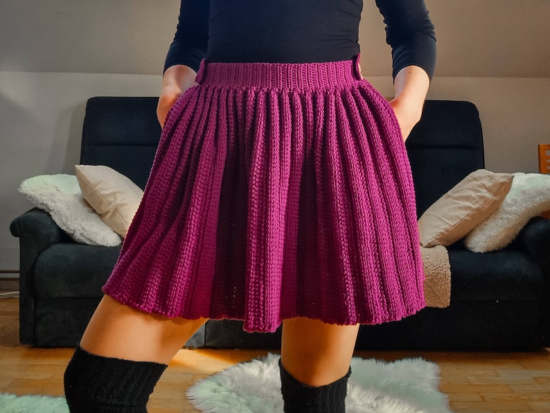 Pode incluir: Uma saia de malha magenta com um design plissado. A saia &eacute; feita de um fio macio e texturizado e tem uma silhueta simples e cl&aacute;ssica.