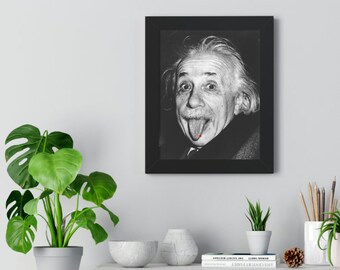 May include: Black and white photo of Albert Einstein sticking his tongue out. The photo is framed in a black frame and hanging on a white wall.