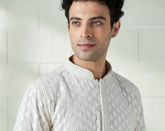May include: Cream-coloured, long-sleeved kurta featuring detailed leaf embroidery. The collar and placket are similarly adorned. The garment has a mandarin collar and a tailored fit, suitable for formal or festive occasions.