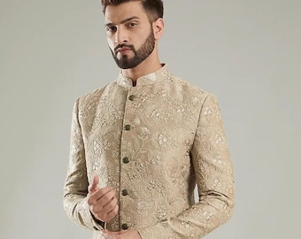 May include: A beige, embroidered jacket with a mandarin collar and button closure. The jacket features a detailed floral pattern and long sleeves. The garment is a formal wear item.
