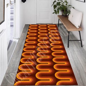 Könnte beinhalten: Ein brauner, orangefarbener und gelber Teppich mit einem wellenförmigen Muster. Der Teppich liegt auf einem Holzboden in einem Flur.