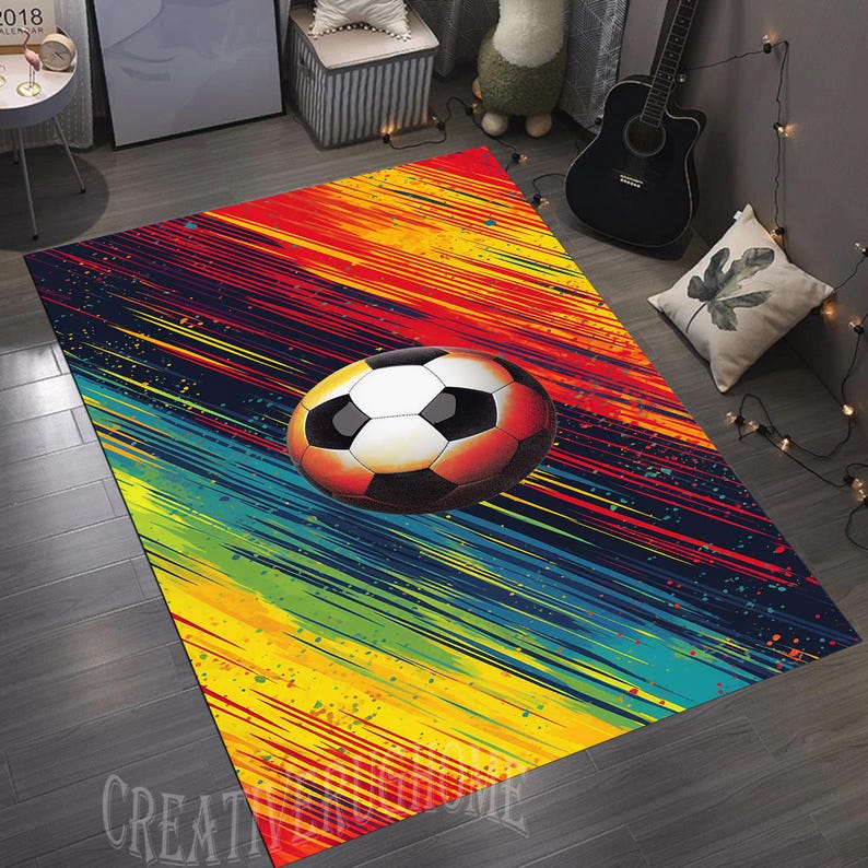 Puede incluir: Una alfombra colorida con un dise&ntilde;o de bal&oacute;n de f&uacute;tbol. La alfombra tiene un fondo negro con rayas amarillas, rojas, verdes y azules. El bal&oacute;n de f&uacute;tbol es blanco con paneles negros.