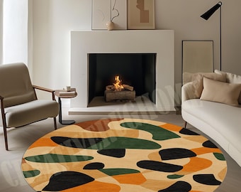 May include: A circular rug featuring a camouflage design in beige, black, green, and orange. The rug is in a living room with a fireplace, chair, and sofa. The rug's diameter is approximately 200 cm.