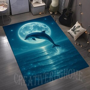 May include: A rectangular rug featuring a dolphin leaping out of the ocean under a full moon. The rug has a blue color scheme with the text "CREATIVERUGHOME" at the bottom. The design evokes a serene, nighttime ocean scene.