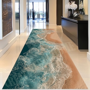 Puede incluir: Una alfombra de pasillo rectangular larga con una impresión fotográfica de alta resolución de una costa oceánica. El diseño muestra olas de mar en tonos turquesa y azul profundo rompiendo sobre una playa de arena color canela.
