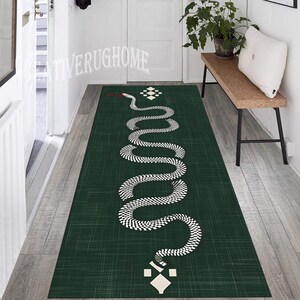 May include: A green and white snake patterned rug with a geometric design. The rug is placed in a hallway with a wooden bench and a potted plant.