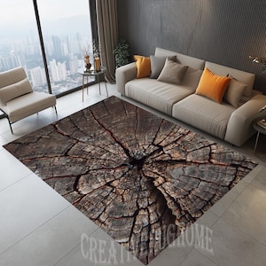May include: A brown and gray area rug with a tree trunk design. The rug has a circular pattern of wood grain and cracks. The rug is in a living room setting with a couch and a window in the background.