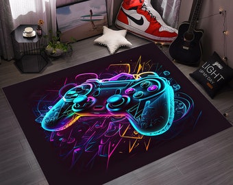 Puede incluir: Una alfombra negra con un diseño de mando de videojuego de color azul neón, rosa y amarillo. El mando está contorneado en negro y tiene un fondo blanco. La alfombra tiene un diseño gráfico de formas y líneas abstractas.