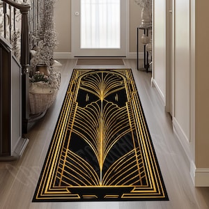 May include: Black and gold Art Deco style runner rug. The rug features a symmetrical design with a central fan-shaped motif and geometric borders. The gold lines contrast against the black background, creating a luxurious look. The rug is rectangular and designed for a hallway.
