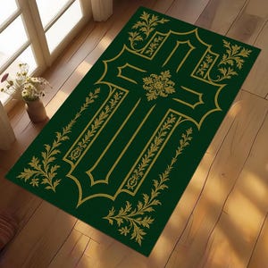 Può includere: Un tappeto rettangolare verde con un disegno a croce dorata e decorazioni floreali. Il tappeto è posizionato su un pavimento in legno vicino a una finestra. Il disegno a croce è centrato con dettagli ornati.