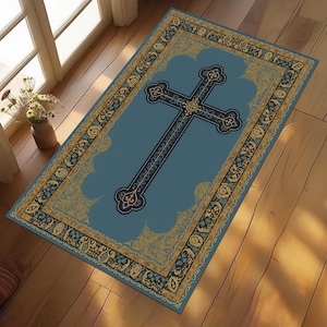 May include: A rectangular blue rug featuring a large cross design. The cross is dark blue with intricate detailing. The rug has a gold and blue decorative border. The rug is placed on a wooden floor.