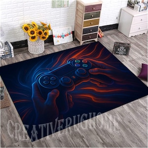 Peut inclure: Tapis rectangulaire avec un design saisissant d'une manette de jeu vidéo tenue dans les mains, avec des accents lumineux bleus et oranges. Le tapis porte le texte "CREATIVE RUGS" en bas. Un article décoratif pour une salle de jeux ou un salon.