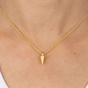 May include: A gold chain necklace with a small gold triangle pendant.