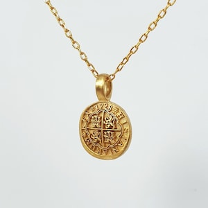 May include: A gold chain necklace with a gold coin pendant featuring a four-leaf clover design and the inscription "1728 HIS",  "british_english":