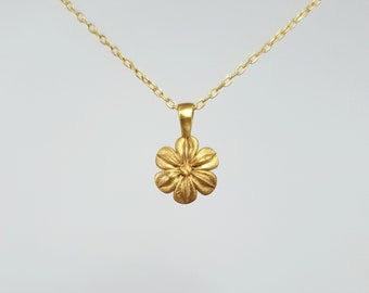 May include: A gold chain necklace with a small, detailed flower pendant.