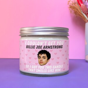 Może przedstawiać: Biały słoik ze świecą z r&oacute;żową etykietą, na kt&oacute;rej znajduje się zdjęcie Billie Joe Armstronga, wokalisty Green Day. Etykieta głosi: "Nie mogłem ci zdobyć Billie Joe Armstronga, więc kupiłem ci tę świecę, kt&oacute;ra pachnie nim."