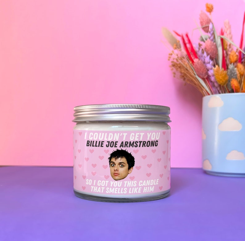 Może przedstawiać: Biały słoik ze świecą z r&oacute;żową etykietą, na kt&oacute;rej znajduje się zdjęcie Billie Joe Armstronga, wokalisty Green Day. Etykieta głosi: "Nie mogłem ci zdobyć Billie Joe Armstronga, więc kupiłem ci tę świecę, kt&oacute;ra pachnie nim."