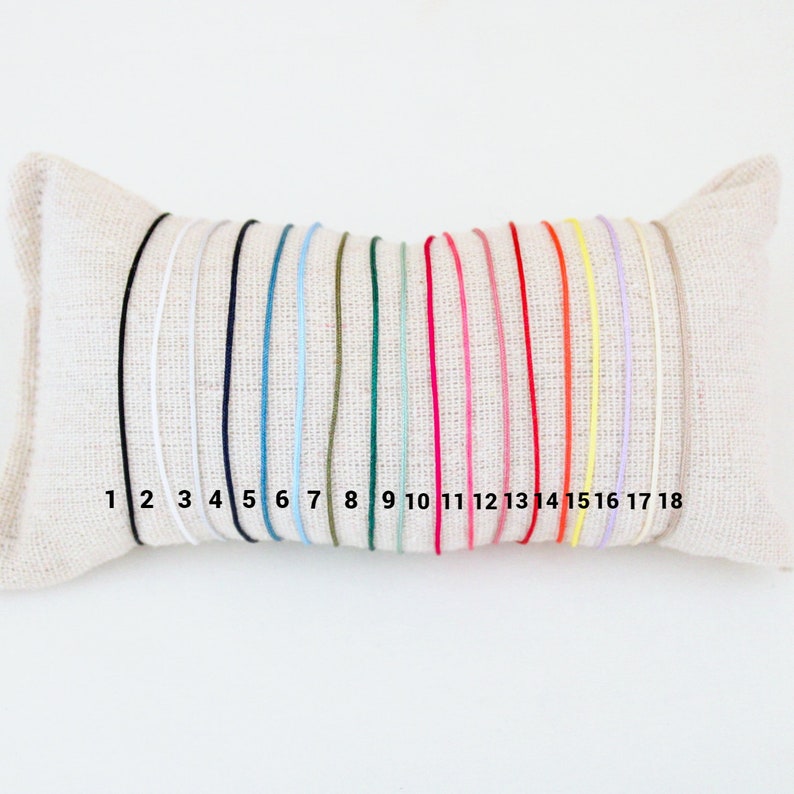 May include: A close-up of 18 different colored cords, numbered 1 through 18, displayed on a white pillow. The cords are all the same thickness and are arranged in a row.