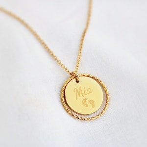 Peut inclure: Collier en or avec un pendentif rond gravé du nom "Mia" et d'une paire d'empreintes de pas.