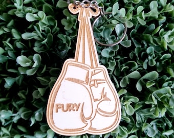 Puede incluir: Llavero de madera con un par de guantes de boxeo, uno de los guantes tiene la palabra "FURY". El llavero está unido a un llavero plateado.