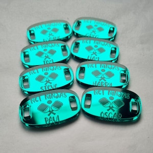 Può includere: Otto etichette verde acqua luminose con la scritta "NET NINJAS" e nomi individuali: Wayne, Tom, Steve, Paul, Greg, Liam, Hardy e Oscar. Ogni etichetta presenta una grafica di racchetta da pickleball.
