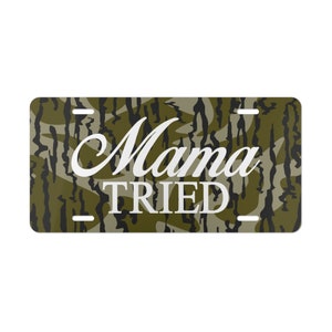 May include: A green and black camouflage patterned license plate with the text "Mama Tried" in white.