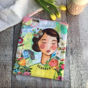 Puede incluir: Una bolsa con cremallera colorida con un dise&ntilde;o floral y la cara de una mujer con la palabra "blessed" impresa en ella.