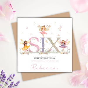May include: A square birthday card with the word "SIX" in large letters, decorated with fairies and flowers. The card reads "Happy 6th Birthday To Our Beautiful Niece Rebecca."