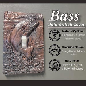 May include: A rectangular light switch cover featuring a relief sculpture of a bass fish jumping out of water. The cover is brown with a textured finish and has a white toggle switch in the center. Text on the right reads Bass Light Switch Cover.