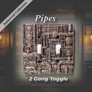 May include: A 2-gang toggle light switch plate featuring a raised, metallic bronze-colored relief design of interconnected pipes, valves, and pressure gauges. The text Industrial Collection, Pipes, and 2 Gang Toggle is visible.