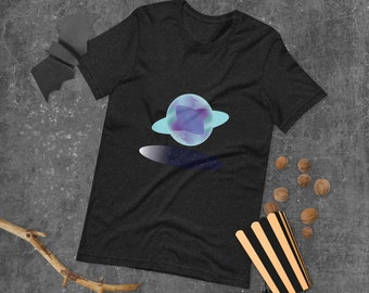 Puede incluir: Una camiseta gris oscuro con un gráfico de un planeta azul y morado con un anillo a su alrededor. El planeta está sobre un fondo azul oscuro con estrellas blancas.