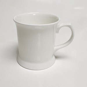 May include: A white ceramic mug with a handle. The mug has a simple design and is perfect for everyday use.