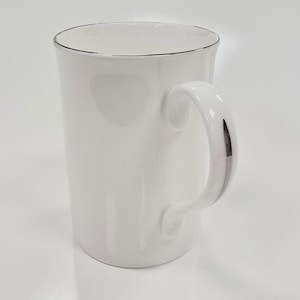 Può includere: Tazza in ceramica bianca con bordo e manico argentati. La tazza ha un design semplice ed è perfetta per l'uso quotidiano.