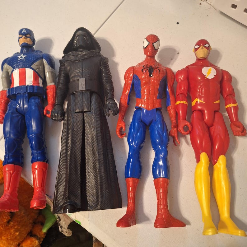 Może przedstawiać: Cztery figurki akcji popularnych postaci z komiks&oacute;w i film&oacute;w. Kapitan Ameryka w kolorze niebieskim, czerwonym i białym. Kylo Ren w kolorze czarnym. Spider-Man w kolorze czerwono-niebieskim. Flash w kolorze czerwono-ż&oacute;łtym.