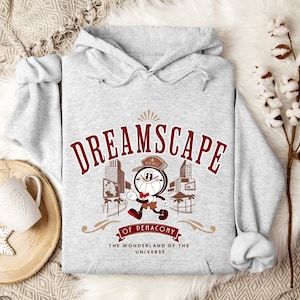 May include: Grey hooded sweatshirt featuring a cartoon character wearing a hat and holding a clock. The text "DREAMSCAPE OF PENACONV THE WONDERLAND OF THE UNIVERSE" is printed on the front.