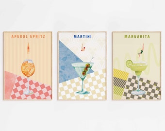 May include: Three framed prints with illustrations of cocktails. Each print features a different cocktail: Aperol Spritz, Martini, and Margarita. Each print has a checkered background and a person diving into the drink.