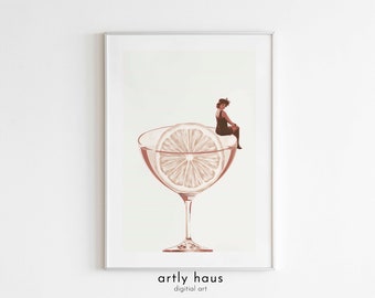 Könnte beinhalten: Ein gerahmter digitaler Kunstdruck zeigt ein großes Cocktailglas mit einer Zitrusfruchtscheibe als Garnitur. Eine kleine Figur in einem dunklen Kleid sitzt auf dem Rand des Glases. Das Kunstwerk ist in monochromen Sepiatönen auf hellem Hintergrund gehalten. Der Text artly haus digital art ist unten mittig in Schwarz gedruckt.