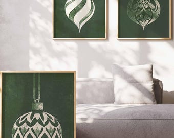 May include: Three framed wall art prints featuring dark green backgrounds with white illustrations of Christmas ornaments. One print shows a striped ornament with a bow, while the other two display intricate, patterned bauble designs.
