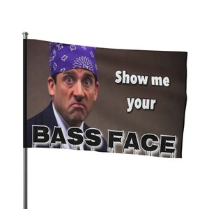 Könnte beinhalten: Eine Flagge mit einem Bild eines Mannes, der ein lilafarbenes Bandana trägt und einen ernsten Gesichtsausdruck hat. Der Text "Show me your bass face" ist auf der Flagge aufgedruckt.