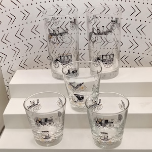May include: A set of three ceramic mugs with a speckled, cream-colored glaze. Each mug features a different hand-painted floral design in shades of blue, green, and yellow. The mugs have a simple, rounded shape and a comfortable handle.