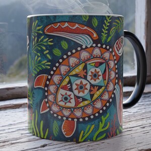 May include: A black coffee mug with a colorful, geometric design of a turtle on a teal background. The turtle has a white shell with orange, yellow, and blue accents.