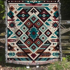 May include: A woven throw blanket with a geometric pattern in shades of brown, red, teal, and white. The pattern features diamonds, arrows, and feathers.